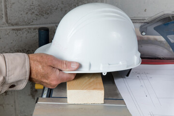 A carpenter in a workshop picks up a hard hat from a table saw
