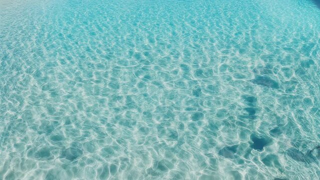 Crystal water in the pool on a sunny day in slow motion. Beautiful transparent clear calm water surface texture with splashes and waves in slow motion
