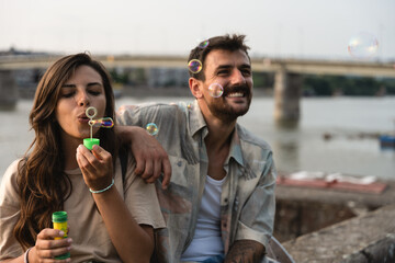 Young hipster stylish vintage couple enjoying life, sitting near the river, spending nice and fun time together. Freedom and lifestyle concept. Close up portrait