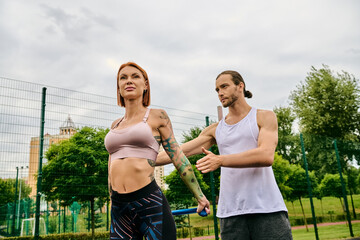A man and woman, wearing sportswear, standing on a tennis court, ready for a challenging workout with personal trainer. - obrazy, fototapety, plakaty