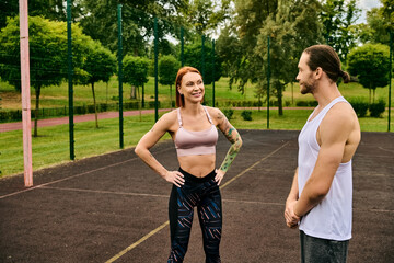 A man and a woman in sportswear stand ready on a tennis court, displaying determination and motivation with their personal trainer.