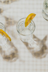 glasses of tonic water and shadow with slice of orange through grid bokeh effect on the foreground