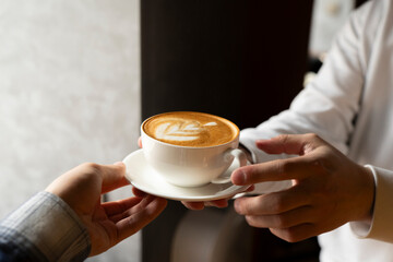Barista Serving a Freshly Made Cappuccino With Artful Foam giving it to the client's hands