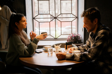 Couple Enjoying Warm Coffee and Conversation at a Cozy Shop Seat near Window