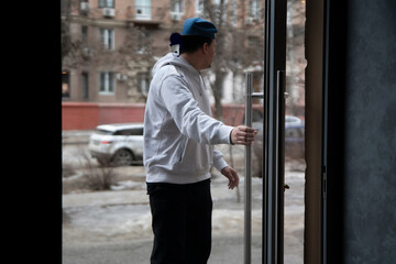 Young Man Entering a Cozy Cafe Through the Front glass Door on a Chilly Afternoon