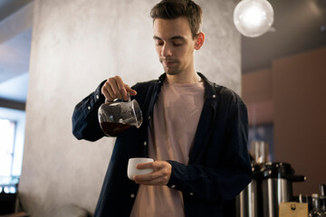 Barista Skillfully Pouring a Stream of Tea Into a Cup at a Modern Cafe