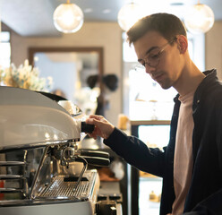 Young Male Barista Preparing Coffee in a Modern Cafe During Morning Rush