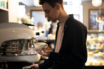 Young Male Barista Preparing Coffee in a Modern Cafe During Morning Rush