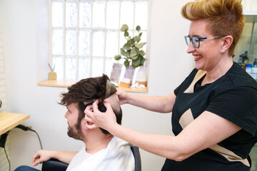 Stylist expertly adjusts hairpiece on smiling client.