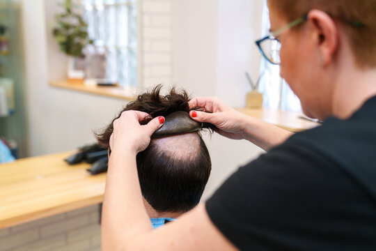 Professional fitting a natural hair prosthesis.