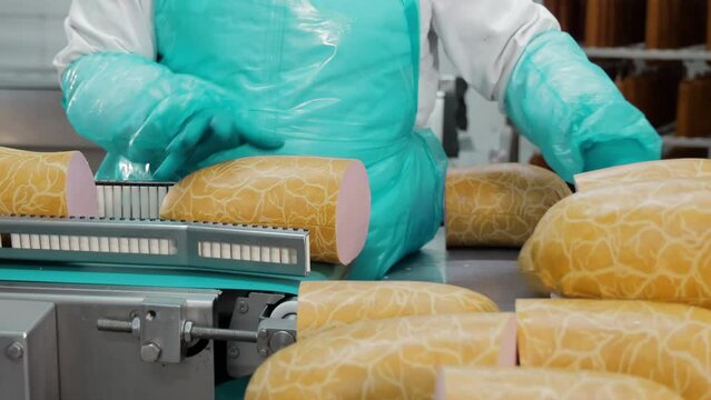 Quality Assurance in Sausage Packing, Worker inspecting sausage packaging on a production line.