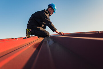 Young man worker in helmet holding, montage roof with blue sky. Roofer work background