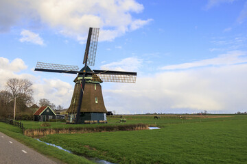 A typical Dutch windmill as a polder mill with paddle wheel for draining the polders in the Netherlands near the town of Schagen