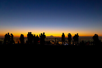 Silhouetted figures observing sunset cityscape - 783251071