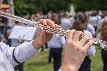 close-up view of a musician's hands playing a transverse flute at an outdoor event