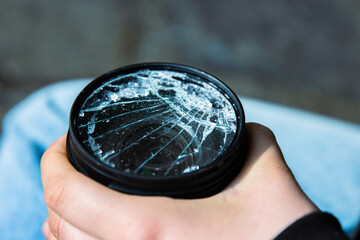 Hands of young photographer holding DSLR photo camera with  broken lens filter glass after if fall...