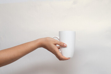Fototapeta na wymiar Una mano de mujer sosteniendo una taza blanca