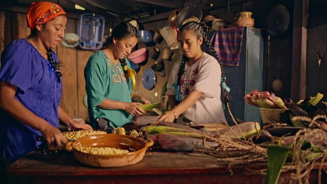 3 Beautiful women of the Xinca ethnic group from northeastern Guatemala, process corn cobs to make sweet tamales called "TASCALES"
