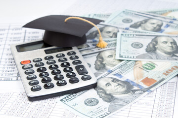 Small graduation cap on calculator, assorted cash. - 783257026