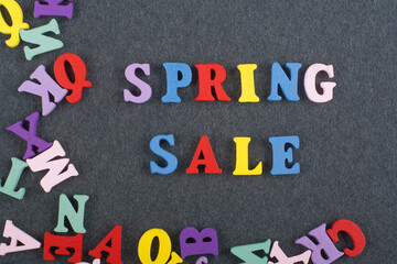 Spring sale word on black board background composed from colorful abc alphabet block wooden letters, copy space for ad text. Learning english concept.