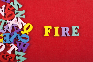FIRE word on red background composed from colorful abc alphabet block wooden letters, copy space...