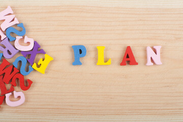 PLAN word on wooden background composed from colorful abc alphabet block wooden letters, copy space...