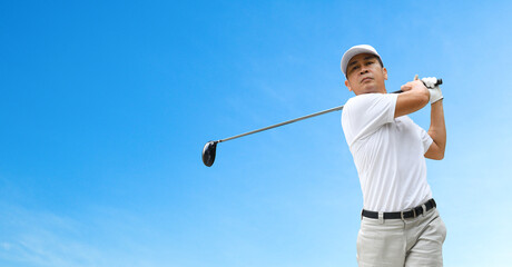 Front view of Golfer hit sweeping driver after hitting golf ball with blue sky background.