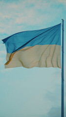 Ukraine flag in blue sky with clouds