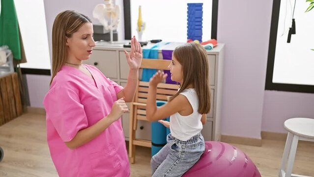 Pediatrician in pink scrubs and child patient playing a coordination game in a clinic room.