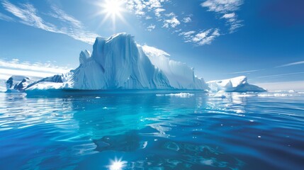 An imposing iceberg with symmetrical formations rises from the ocean as the sun shines brightly overhead. The ice mass contrasts with the deep blue waters, creating a stunning natural scene. - 783280007