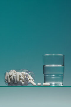 White drugs in a glass bottle and a glass of water