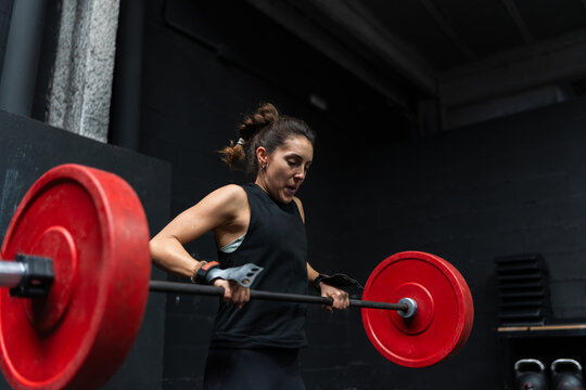 Woman lifting a barbell in a crossfit gym.