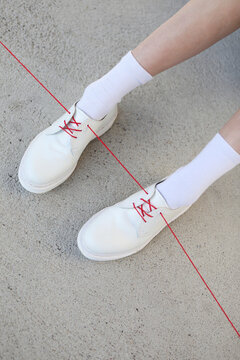 White shoes with one red lace/ribbon. Illustration of red thread 