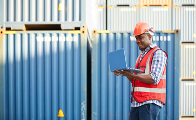 African factory worker or engineer working on laptop computer in containers warehouse storage