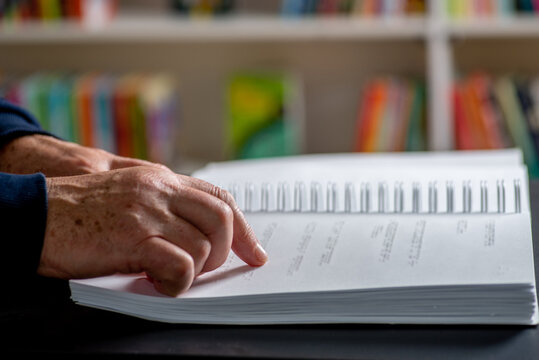 Male elderly fingers reading a book page with braille