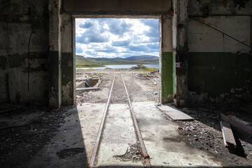 Russia. Kola Superdeep Borehole, destroyed buildings. Rails go out of darkness into light