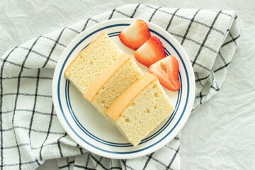Three slices of homemade vanilla sponge cake with sliced strawberries.