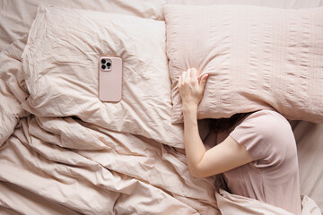 Top view of the person sleeps alone in bed near phone.