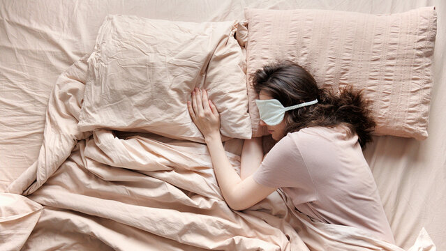 Top view of the person sleeps alone in bed in  sleep mask.