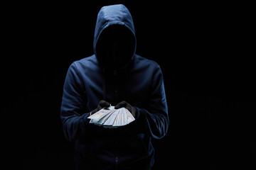 Unsafe transactions on the Internet. Hacker holding cash. Anonymous offers money. . Computer technology or cyber crime concept.
