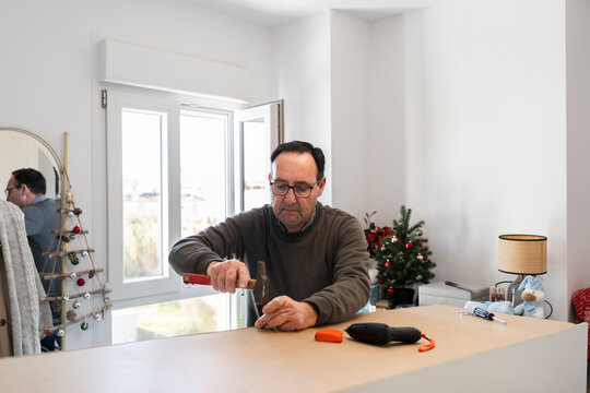 man using a hammer to assemble a piece of furniture at home.
