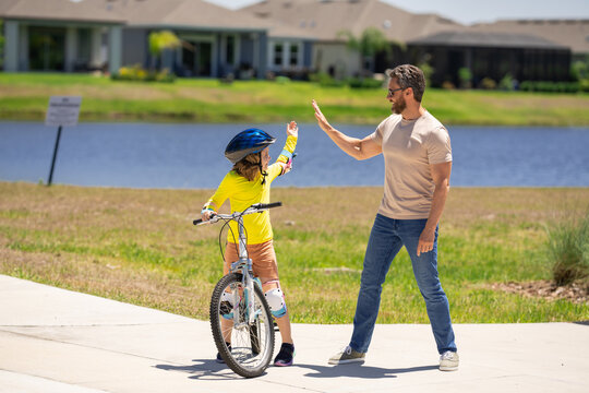 Fathers day. Father and son riding a bike on the road at the fathers day. Concept of friendly family. Parents and children friends. Father and son riding a bike outdoor on summer day. Child first bike