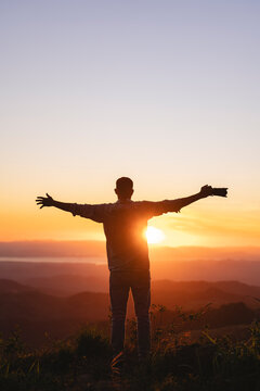 Man with arms outstretched watching the sunset