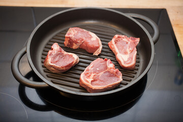 Lamb chops on a griddle pan cooking on a hob