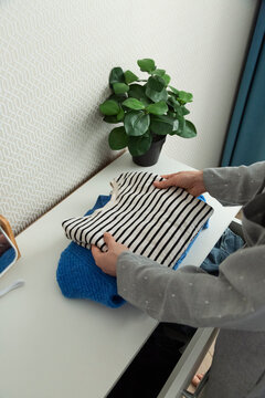 Crop woman folding clothes on commode