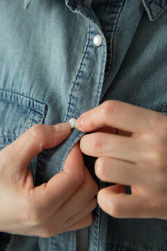 Crop woman buttoning up shirt