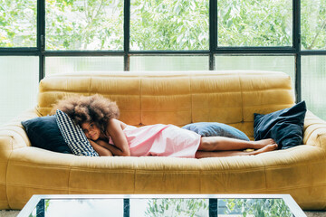 Young girl napping on a comfy sofa by the window