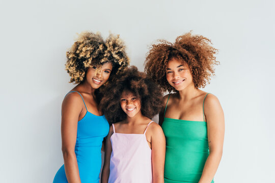 Three smiling women with curly afro hair posing together