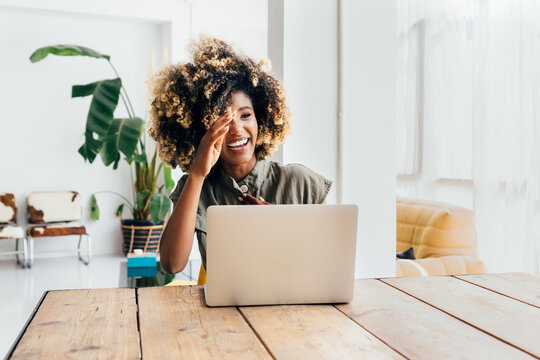 Cheerful afro woman using laptop at home