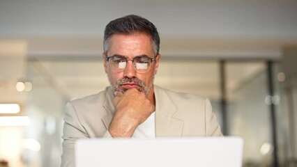 Busy mature business man trader broker analyst investor analyzing stock exchange trade crypto financial market looking at computer screen in glasses with charts reflection thinking of investing money.
